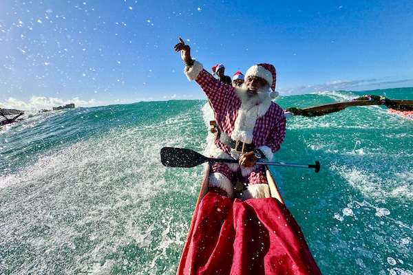 Santa riding a wave on a canoe